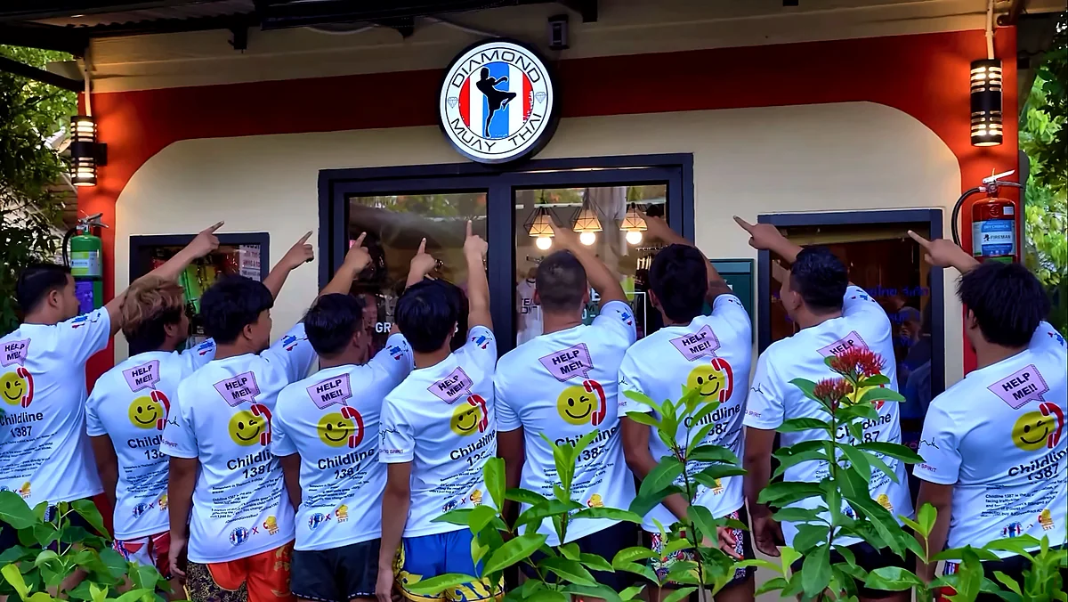 Diamond Muay Thai trainers pointing up at the Diamond Muay Thai gym sign